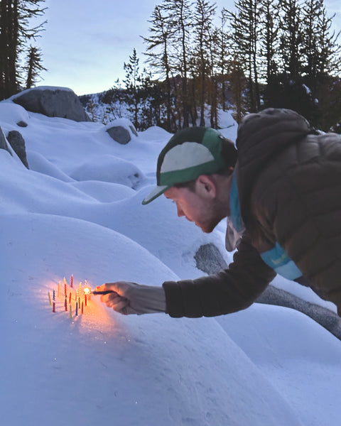 Kyle's partner lights candles in the snow for his birthday