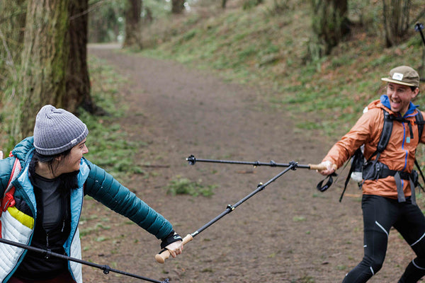 Two hikers mock sword fight with trekking poles