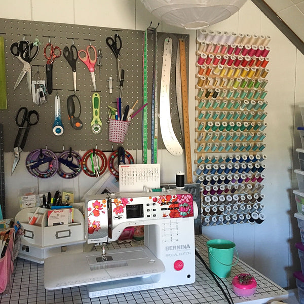 Marshmueller Studio sewing area with sewing machine, pegboard tool storage, and thread rack