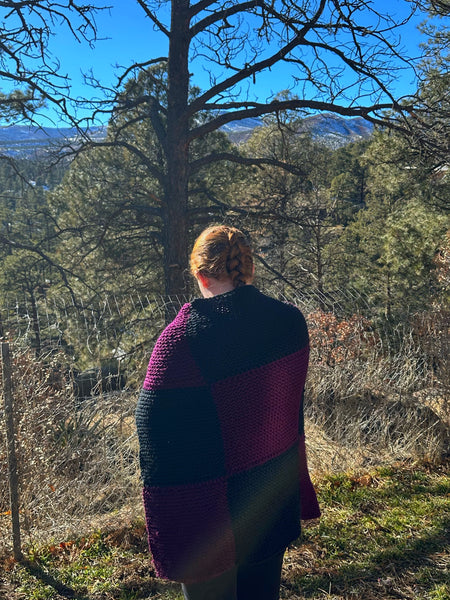 Woman wrapped in the Lent Prayer Blanket looking out at trees
