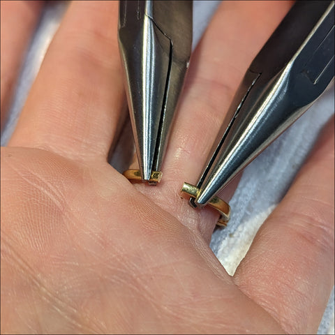 jeweler using pliers to carefully open cut ring