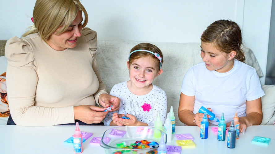 Three people creating crafts at a table, smiling and having fun.