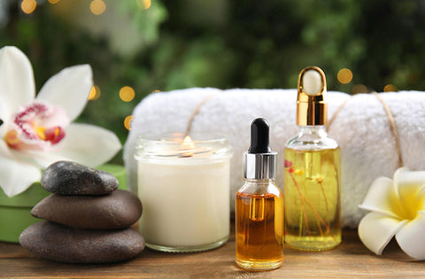 essential oils with towel, flower and candle are on table