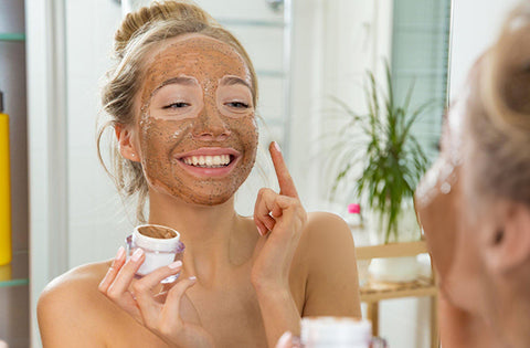 lady is applying face scrub on her face