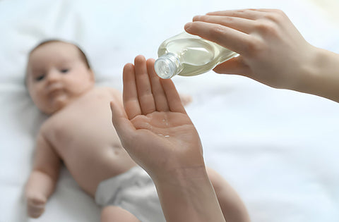 mother is pouring baby oil on her hand for baby massage