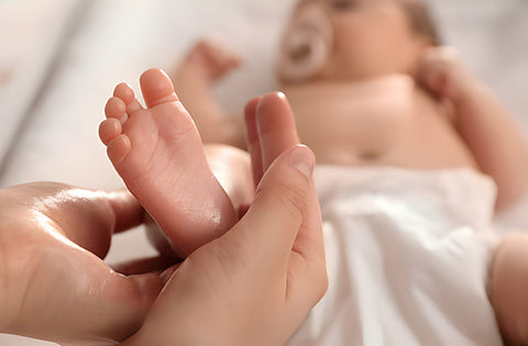 mother is giving baby gentle stroke while massage baby feet