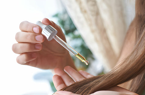 lady is applying rosemary hair oil on hairs