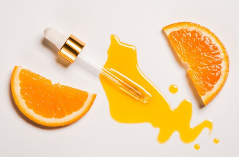 serum with vitamin c applicator and slices of oranges are on table
