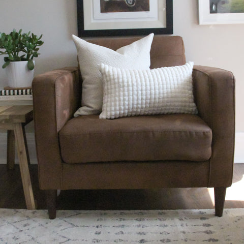 Brown chair with white throw pillows