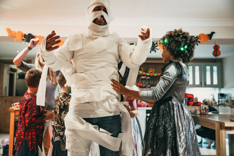 Kids wrapping dad into a mummy for Halloween