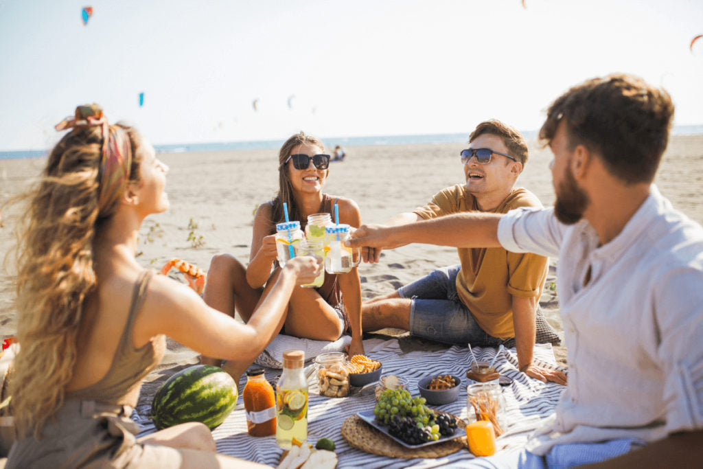 Friends enjoying on the beach and drinking lemonade.