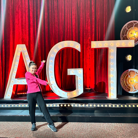 Koko Hayashi presenting her face yoga techniques on the America's Got Talent stage, engaging with the audience and judges.