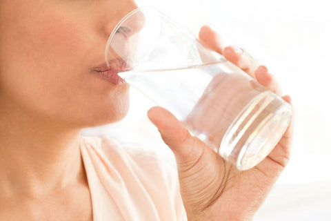 A person drinking alkaline water from a glass