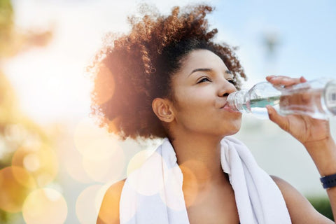 A person drinking alkaline water from a bottle