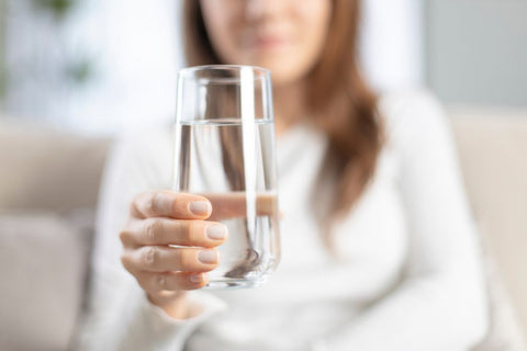 A person holding a glass of alkaline water