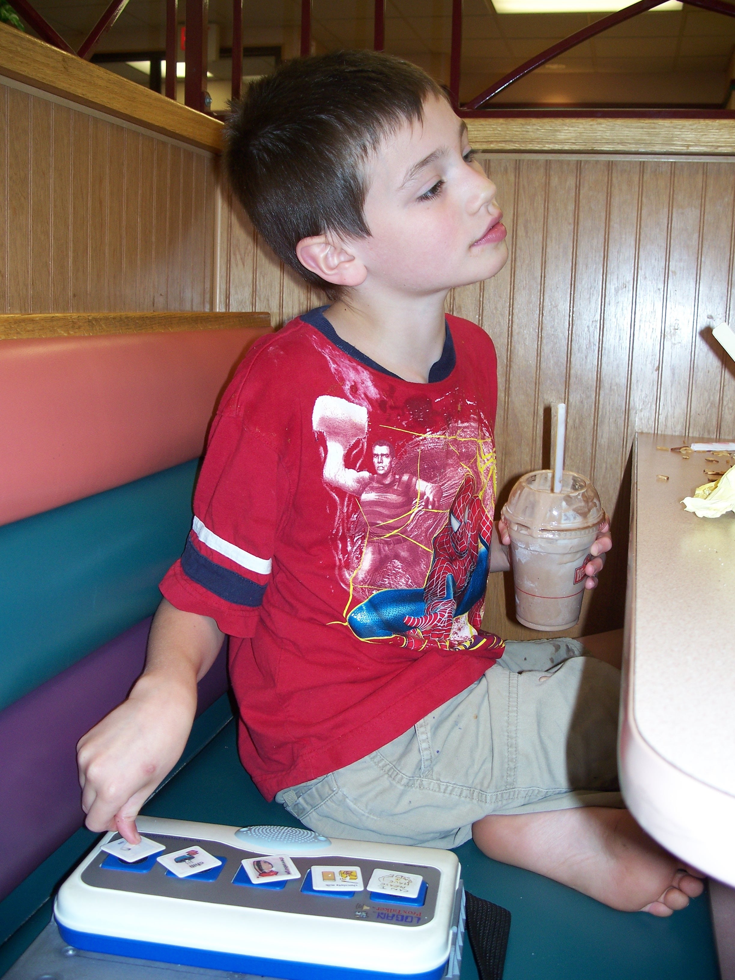 Logan sitting in a booth at Wendy's with the ProxTalker and a chocolate frosty