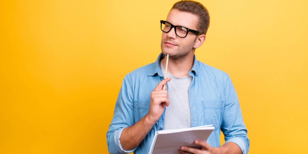 homme à lunettes en chemise bleu qui réfléchit