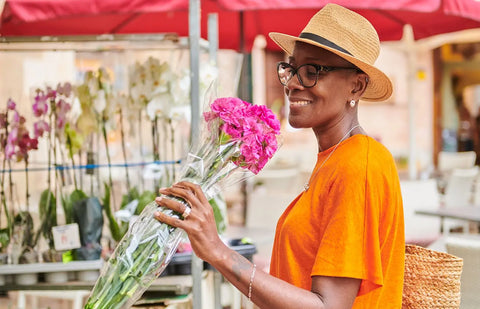 A gender diverse person smells flowers at a market while building an understanding of menopause for gender diverse individuals