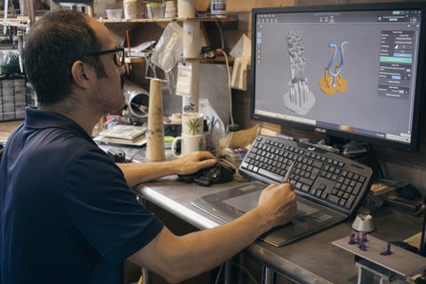 man sitting at computer using graphics software to design jewelry