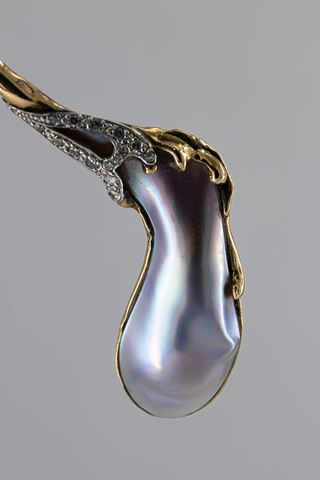 close up image of pearl necklace with large tear drop shaped purple and black hued pearl