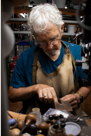 man at workbench using a jewelry tool