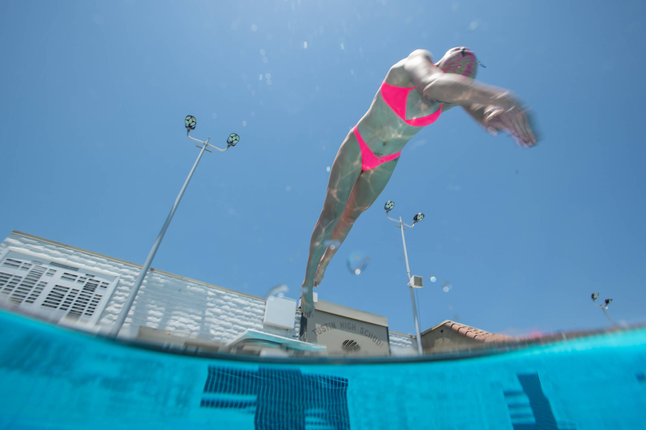Olivia Smoliga wearing a pink bikini, diving into the pool