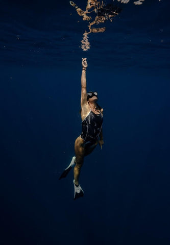 a woman in a JOLYN one piece swimsuit, underwater