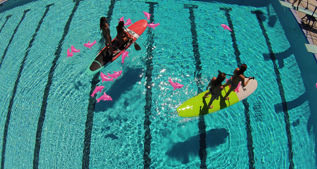 women on a paddleboard wearing JOLYN swimsuits
