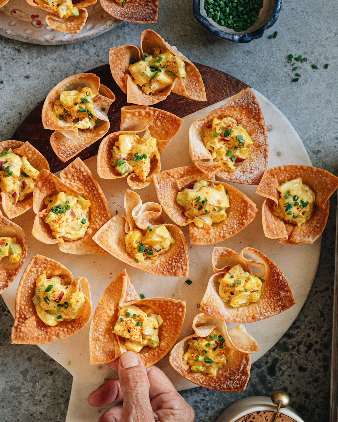 A crowd-friendly platter of crispy wonton cups stuffed with a creamy curried egg salad filling and topped with chili flakes | peteandgerrys.com