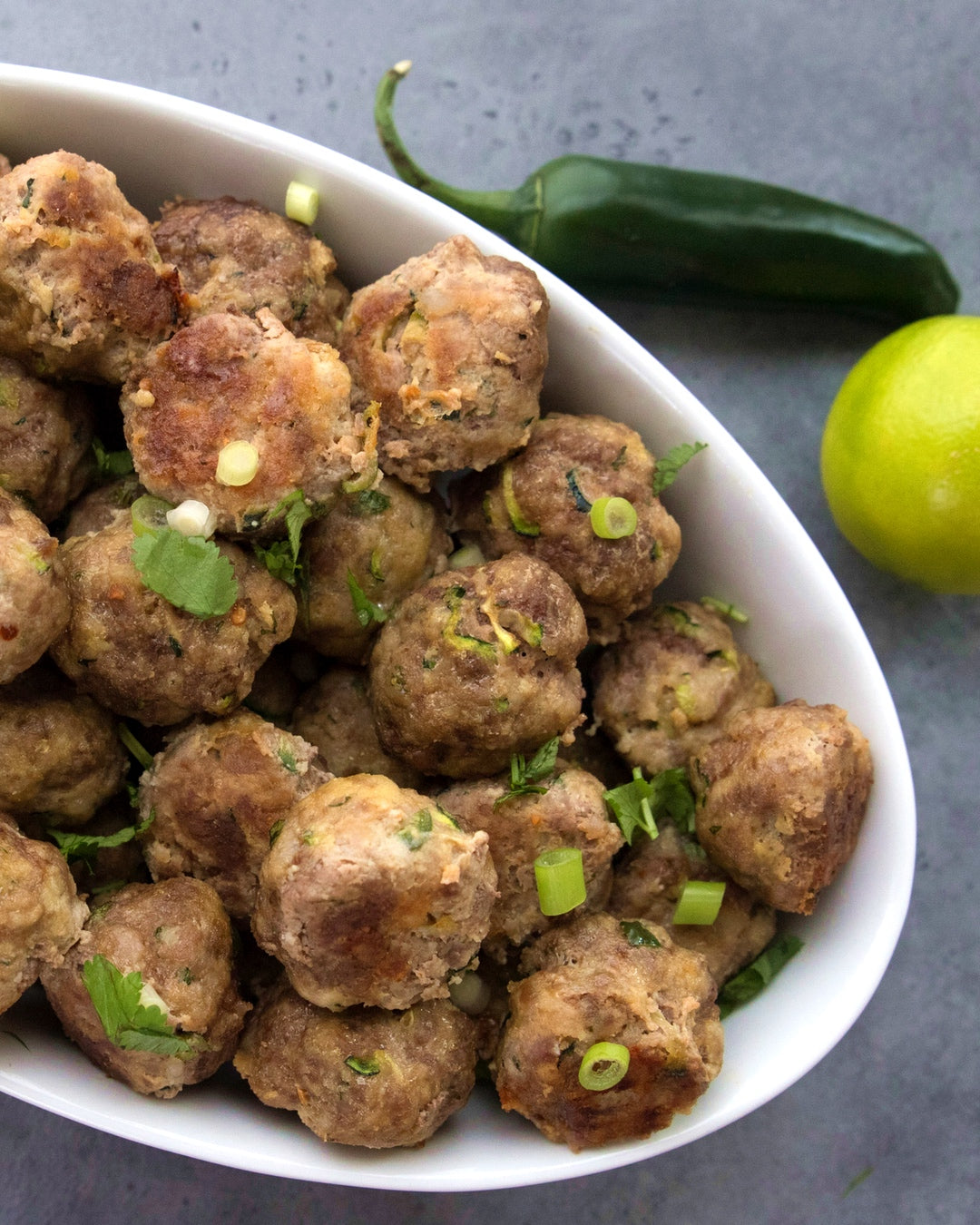 A shareable  low-carb recipe for Thai-inspired meatballs made with ground pork, zucchini, fresh ginger, and green onion. | peteandgerrys.com