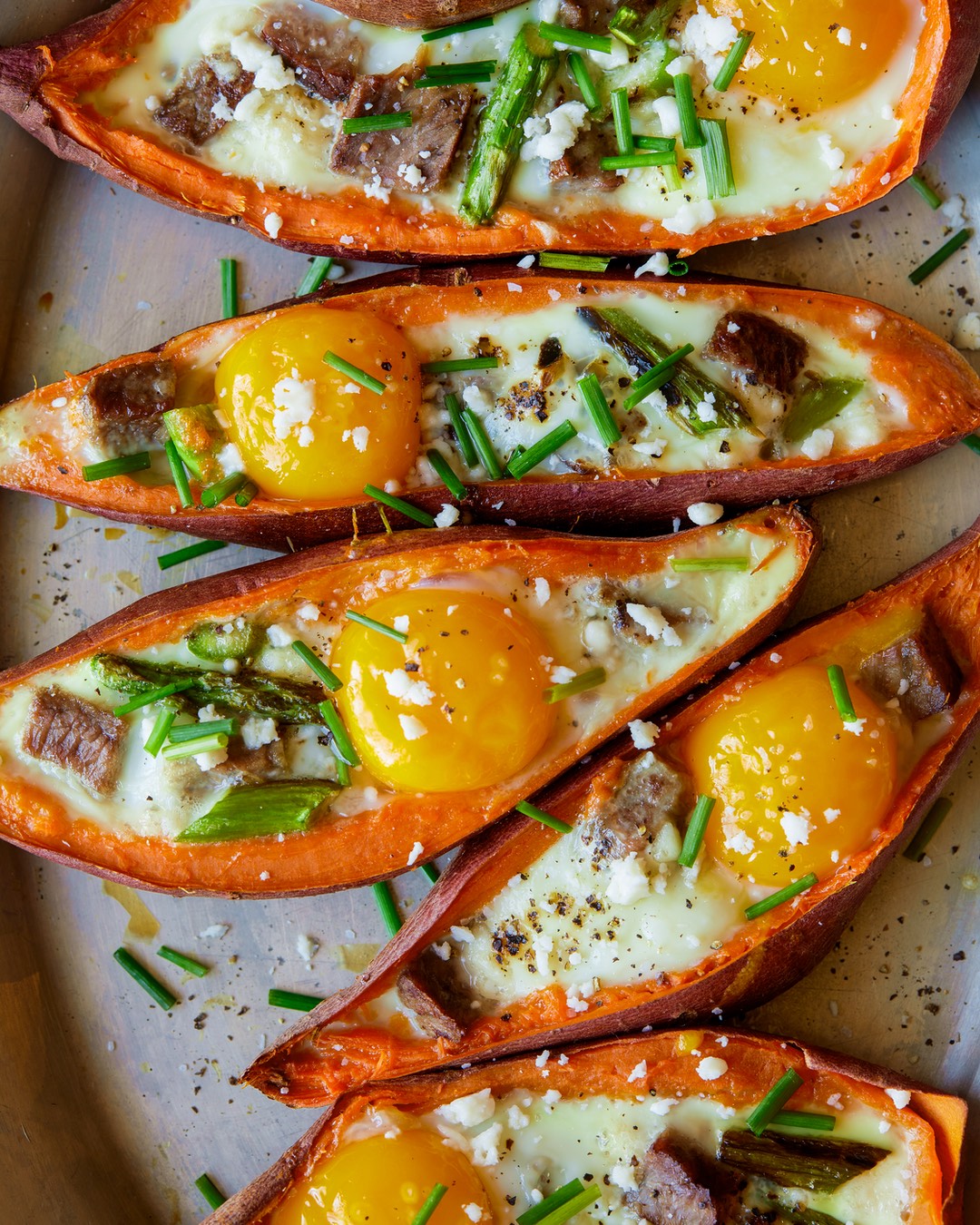 A crowd-friendly breakfast recipe for twice baked sweet potatoes piled high with cheese, steak and sunny eggs. | peteandgerrys.com