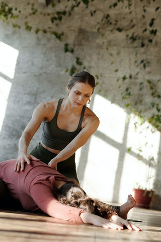 female personal trainer helping female stretch