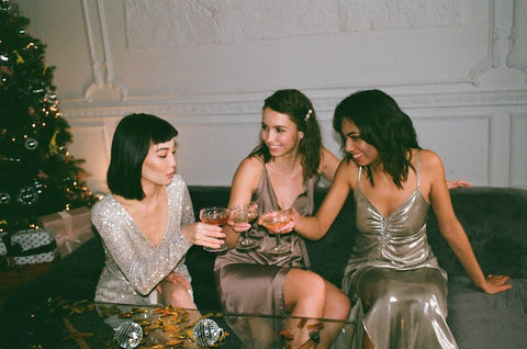 three glowing females in sparkly dresses at a festive party