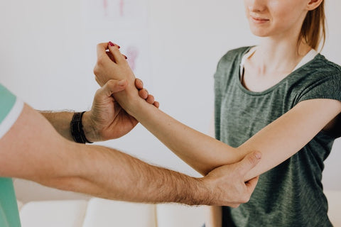 female having her arm looked at by a physical therapist