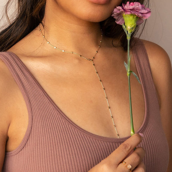 woman holding flower wearing a gold lariat