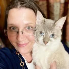 woman with glasses holding a white cat with beautiful blue eyes