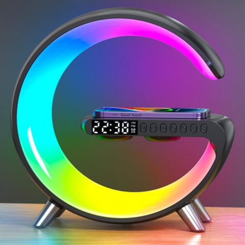 Image of the Intelligent G-Shaped LED Lamp, an innovative home accessory with a unique circular design featuring a gradient of LED lights in vibrant colors. The lamp has a modern black frame with a G-shaped curve and a built-in digital clock display. At the base, there's a wireless charging pad, and the lamp also boasts a built-in Bluetooth speaker, combining multiple functionalities into one elegant device. It is depicted as a sophisticated and multifunctional piece that fits seamlessly into contemporary home decor while offering adjustable lighting, high-quality audio, and wireless charging for Qi-enabled devices.