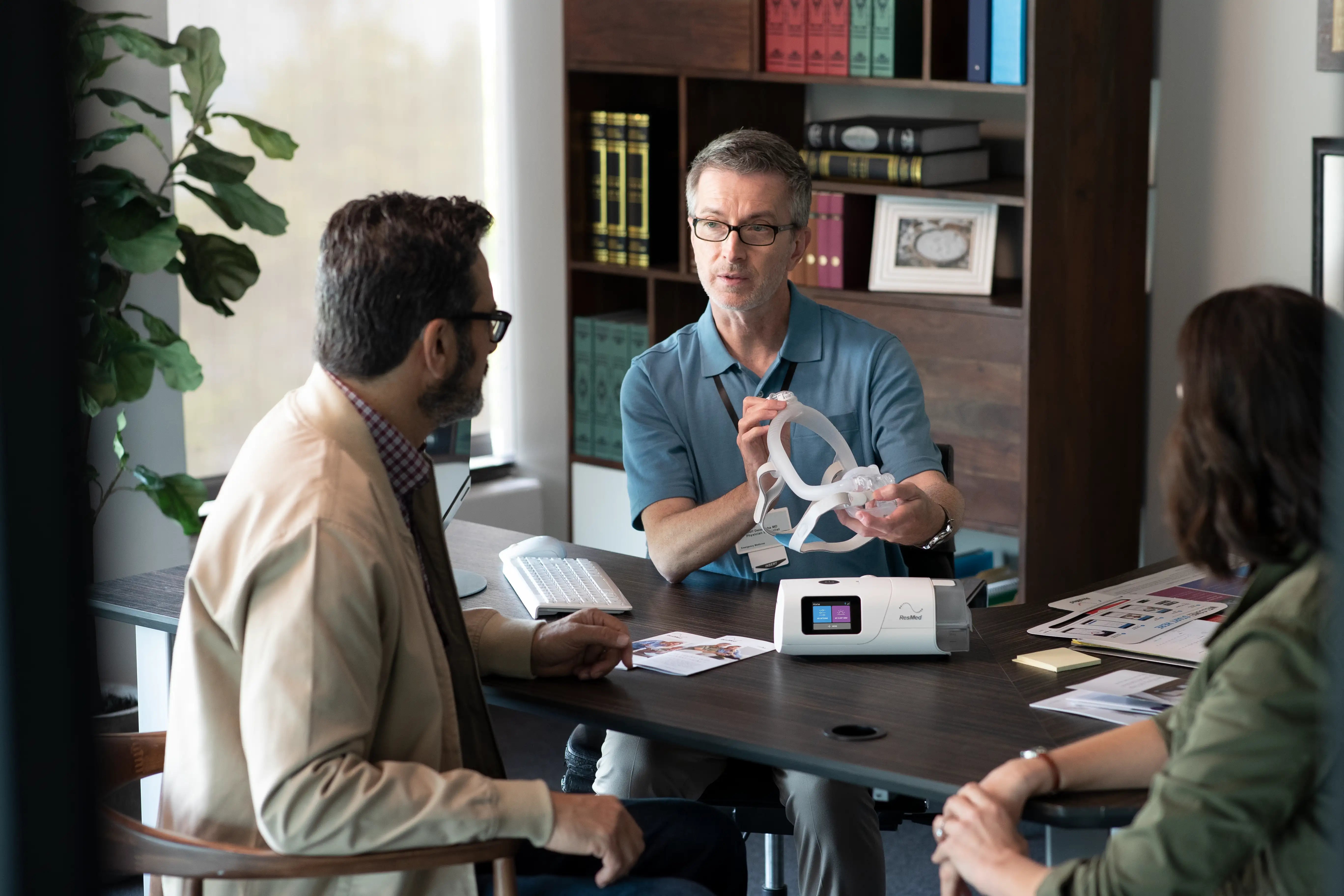 A man holding the CPAP machine and explaining it to his clients