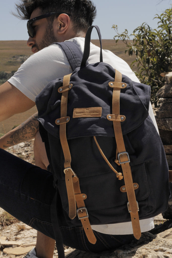 a man wearing a white shirt, with a navy/brown backpack and jeans 