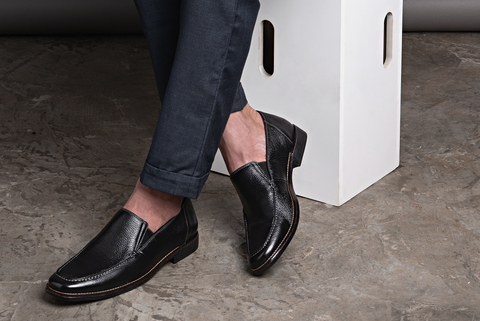 Crossed legs wearing a Sandro Moscoloni black loafer. 