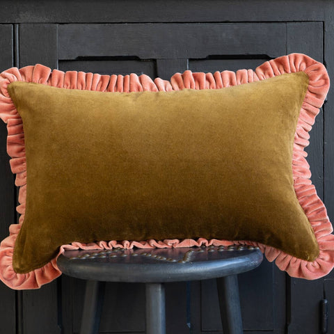 Lifetsyle image of the Moss Green Velvet Cushion With Pink Ruffle displayed on a black stool in front of a black cabinet.