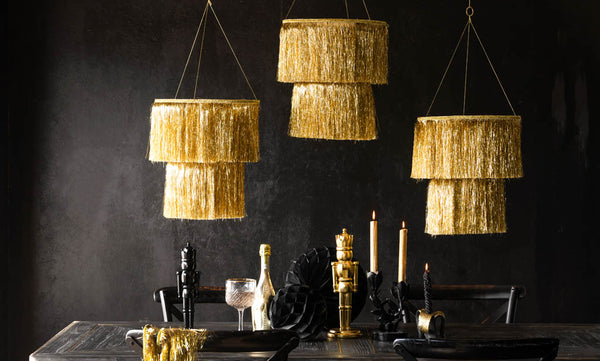 A black Christmas table setting with gold fringe chandeliers hanging from the ceiling