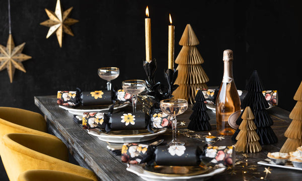 A black and gold tablescape scene with floral Christmas crackers.