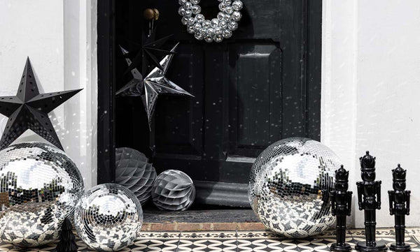 A front door decorated for a Christmas party with silver disco balls and black nutcrackers.