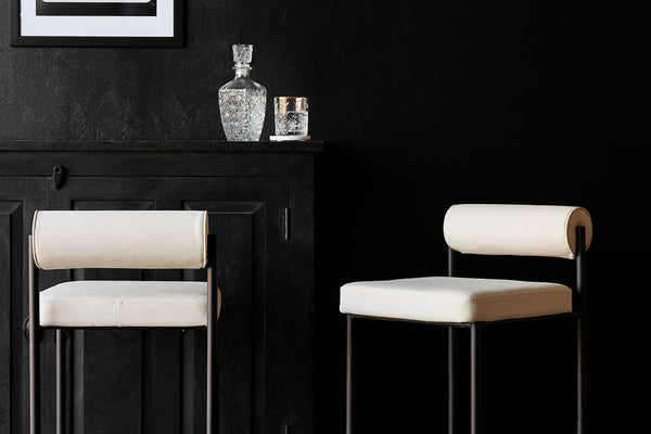 white roll back bar stools in a dark room