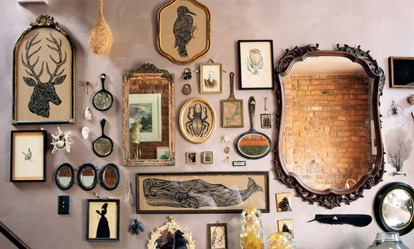 A unique gallery wall of art with mirrors, objects, shells and prints on display.