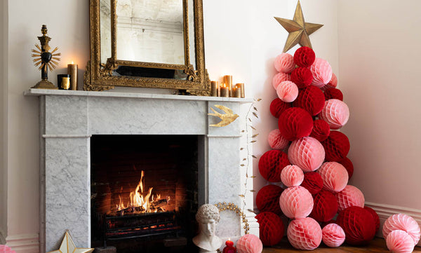 red and pink honeycomb ball Christmas tree next to a marble fireplace