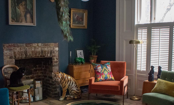 Image of the living room of Tom & Jamie's London home with dark walls and a statement burnt orange armchair