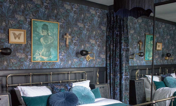 A maximalist bedroom with blue and black patterned walls.