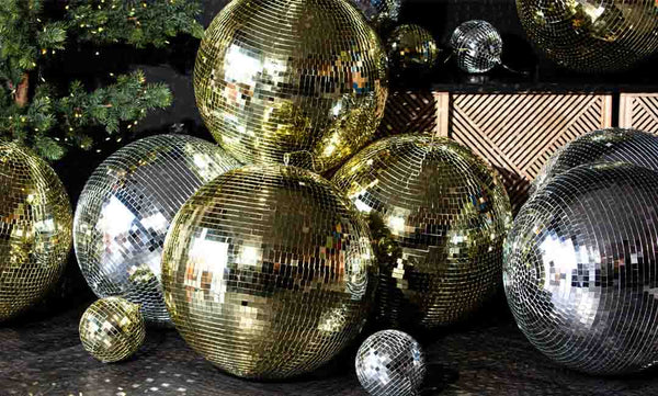 An image of glamorous gold and silver disco balls under a Christmas tree